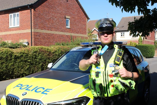 Police officer standing in front of a police car holding a drug wipe