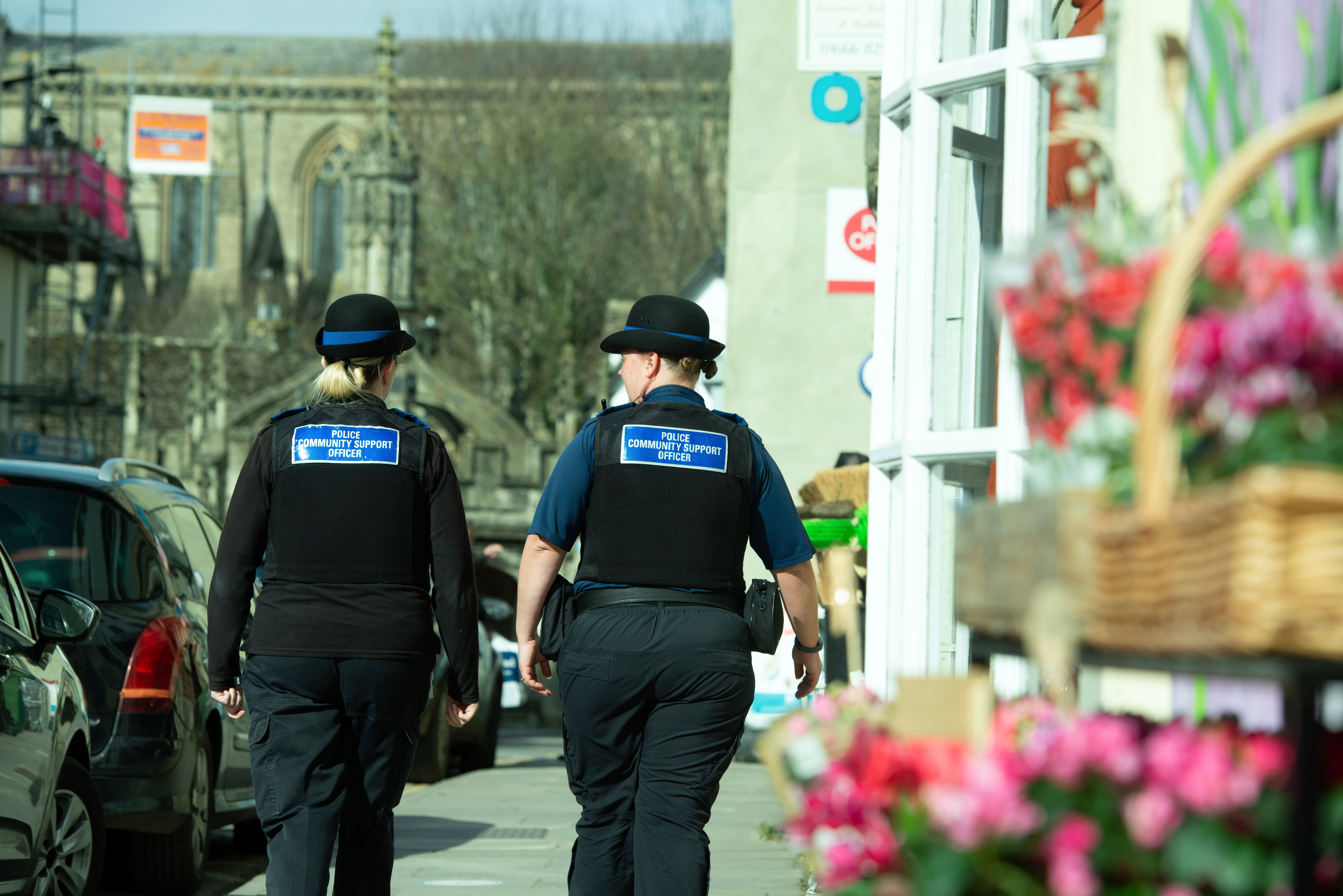Two PCSOs walking away, down the street passed a flower shop