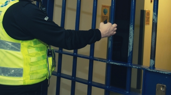 Police officer shutting metal custody gate